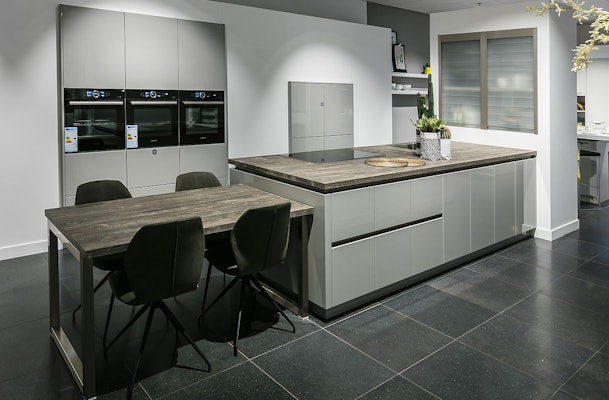 Grijze hoogglans keuken met houten werkbladen