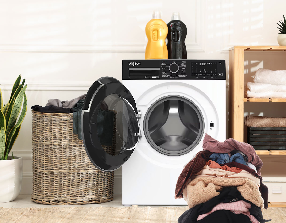 Grote Whirlpool-wasmachine met ruime trommel, open deur en een grote stapel wasgoed in een moderne wasruimte.