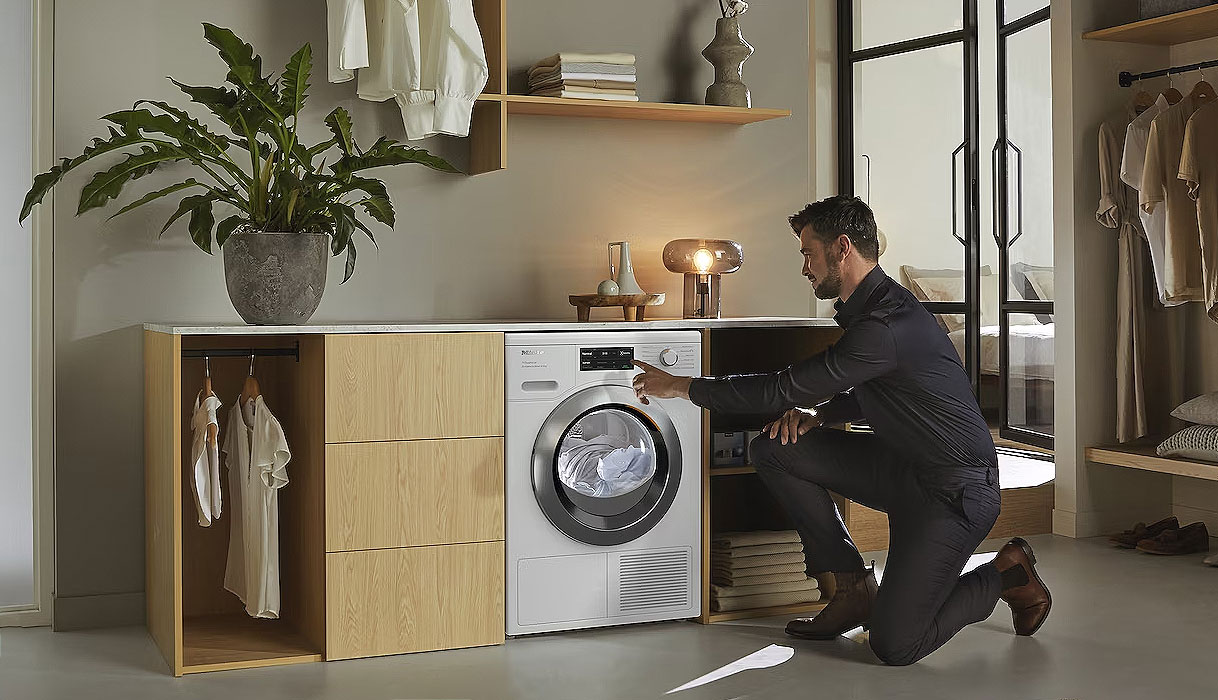 Miele wasdroger DryCare 40 functie - man gebruikt droger in wasruimte