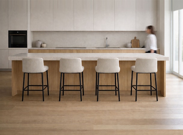 Vijf beige barkrukken met zwart frame op een rij naast een lang houten keukeneiland in een lichte moderne keuken