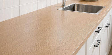 Houten werkblad in landelijke keuken met inbouwspoelbak, kraan en greepjes op fronten