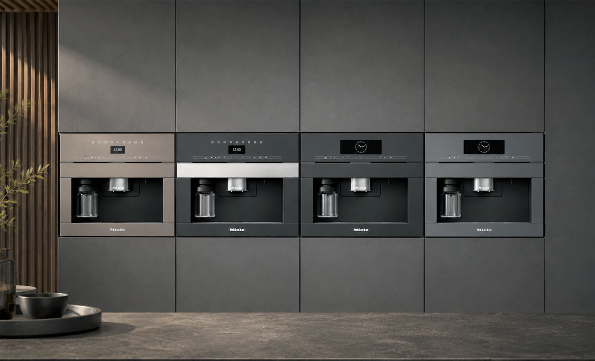Vier modellen Miele inbouw koffiemachines naast elkaar in een donkere kastenwand