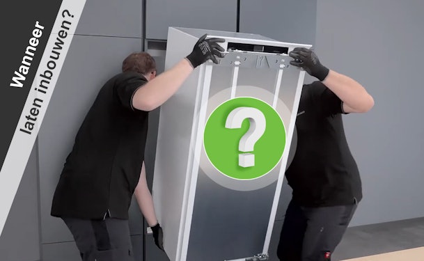 Twee monteurs die een koelkast tillen als voorbeeld van situaties waarin professionele inbouw nodig is