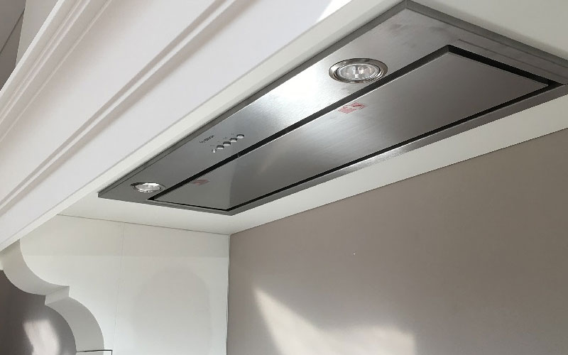 Inbouwunit afzuigkap weggewerkt in een schouw of maatwerkkast, waarbij alleen de onderzijde van de afzuigkap zichtbaar is.