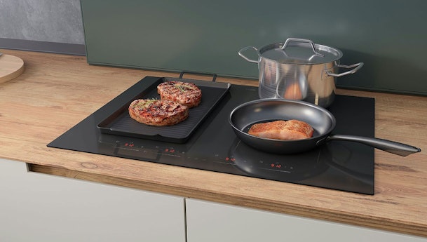 70 cm inductiekookplaat met twee pannen en een braadslede op gekoppelde kookzones