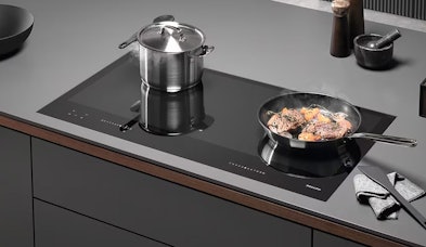 Miele inductiekookplaat 90 cm met meerdere pannen en koekenpan in moderne keuken