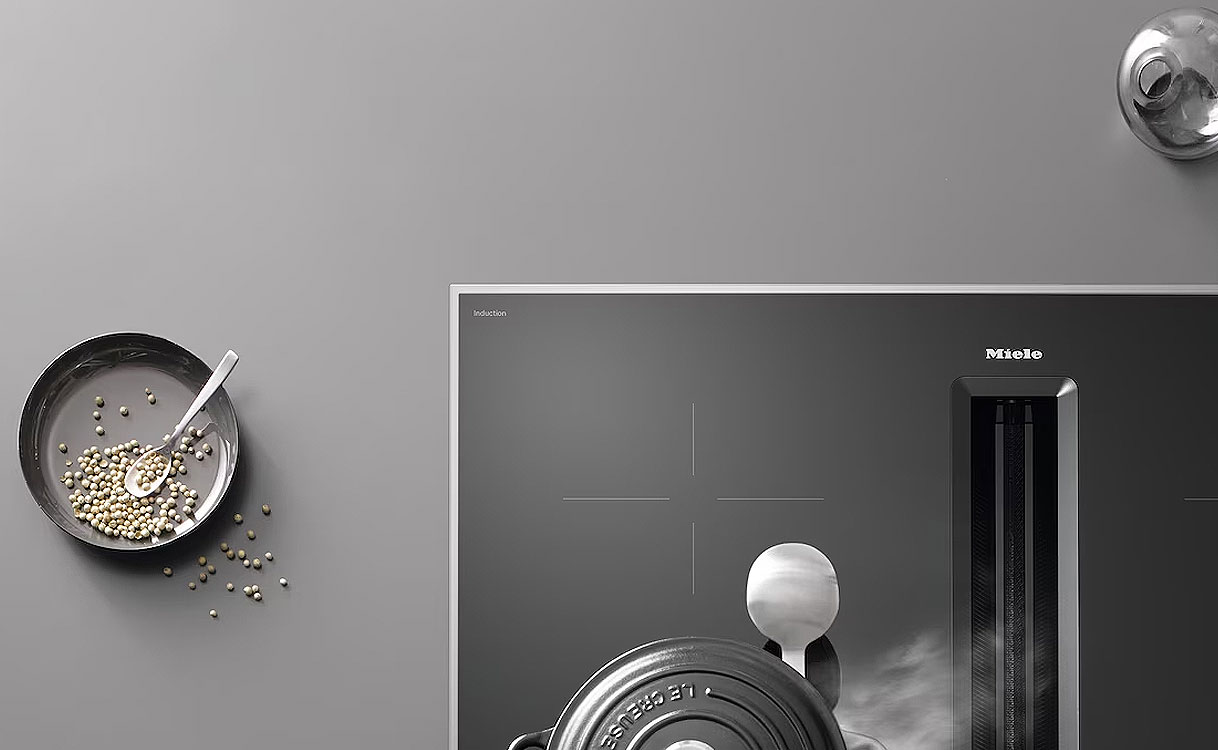 Miele inductiekookplaat met roestvrijstalen randlijst en kookpannen op werkblad