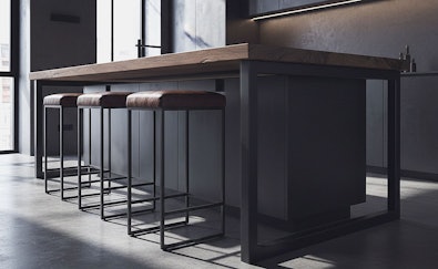Vier industriële barkrukken met zwart stalen frame en houten zitting op een rij naast een donker houten keukeneiland