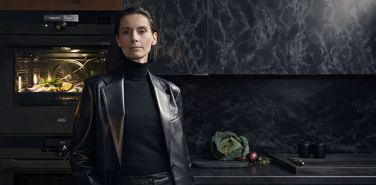 Vrouw naast AEG stoom magnetron in donkere keuken voor keuzehulp bij inhoud en vermogen