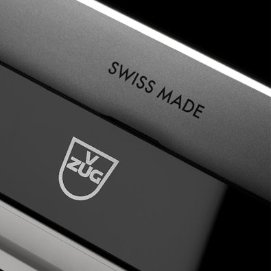Close-up van V-ZUG vaatwasser met Swiss Made-logo; intelligente sensoren passen programma, water- en energieverbruik automatisch aan op belading en vervuiling.