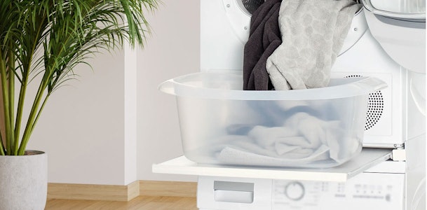Tussenstuk met uitschuifbare lade tussen wasmachine en droger met wasmand erop