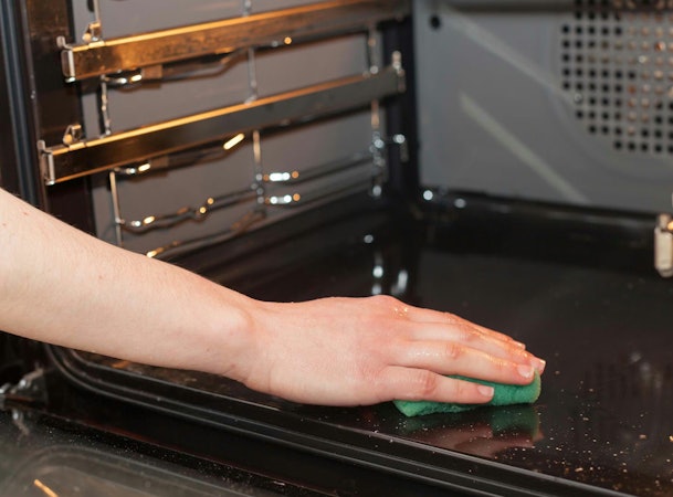 Hand reinigt bodem van oven zonder katalytische coating