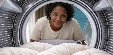 Vrouw die wit katoenen dekbed in droger legt op maximaal 40 graden