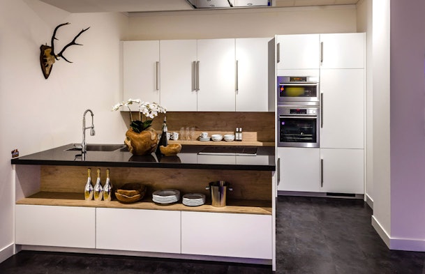 Witte opstelling met houtaccent en zwart werkblad