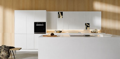 Moderne keuken met groot wit kookeiland en lichte houten wandkasten