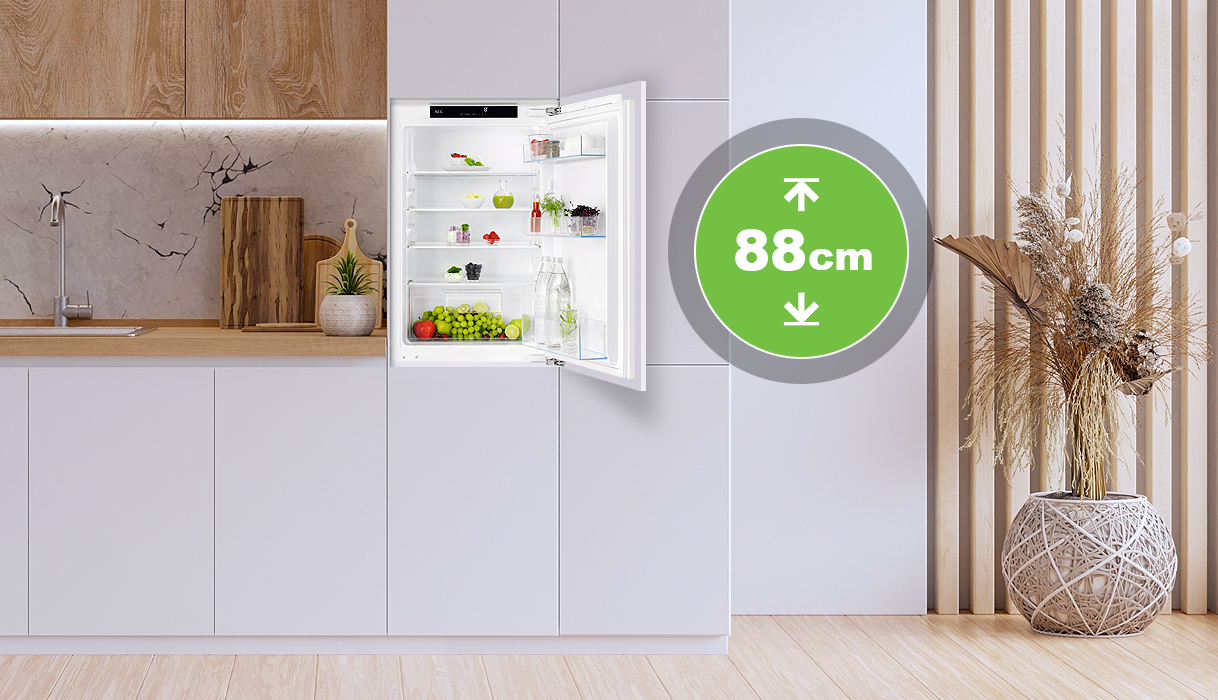 Kleine inbouwkoelkast van 88 cm nishoogte geopend in een moderne keuken, met overzichtelijke indeling en verse producten.