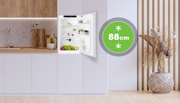 Kleine inbouwkoelkast van 88 cm nishoogte geopend in een moderne keuken, met overzichtelijke indeling en verse producten.