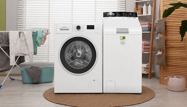 Voorlader en bovenlader naast elkaar, waarbij het verschil in formaat en breedte van een kleine wasmachine zichtbaar is.