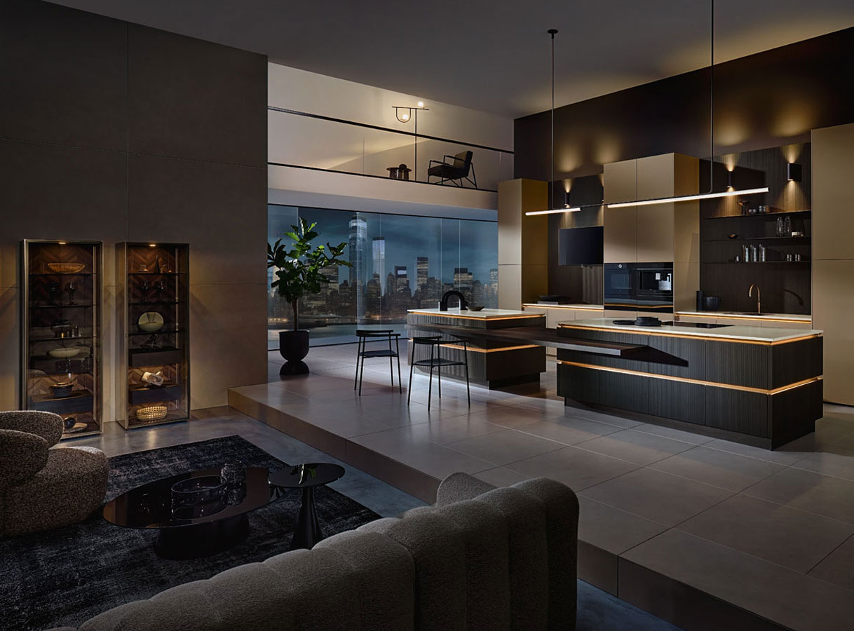 Luxe moderne keuken met donkere kasten, kookeiland en warme verlichting in open woonruimte.