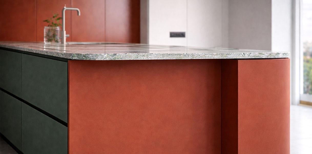 Kookeiland met terracotta kleuraccent en natuurstenen werkblad in moderne keuken