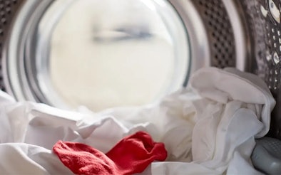 Rode sok tussen witte was in de trommel van een wasmachine