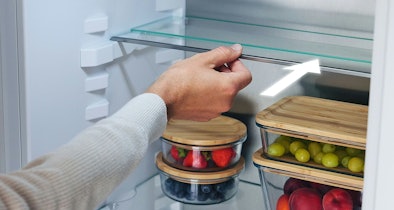 Hand die een glasplateau in een inbouwkoelkast verschuift om de indeling aan te passen.
