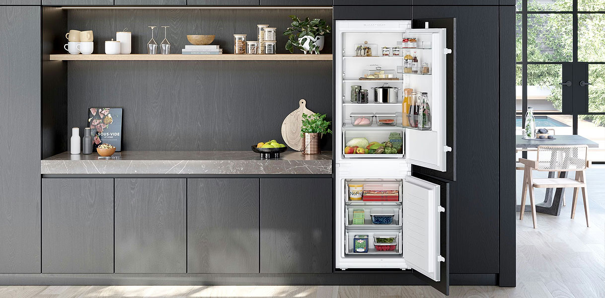 Volwaardige inbouw koel-vriescombinatie van 178 cm hoog in een moderne donkere keuken met open deuren.