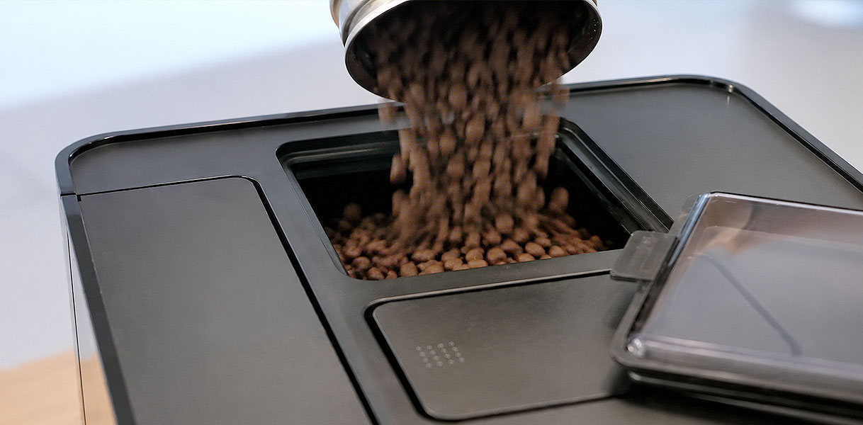 Open bonenreservoir van een koffiemachine met koffiebonen van bovenaf gezien