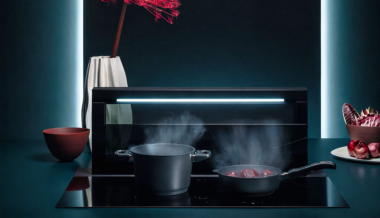 Kookplaat met geïntegreerde afzuiging in een donkere luxe keuken als illustratie van het premium karakter van dit type kookplaat