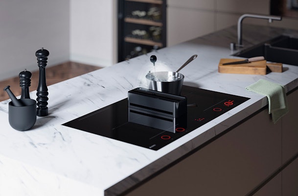 Kookplaat met ingebouwde afzuiging op marmeren kookeiland in moderne keuken