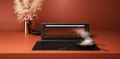 Inductiekookplaat met pan en uitschuifbare downdraft afzuigkap met dampafzuiging