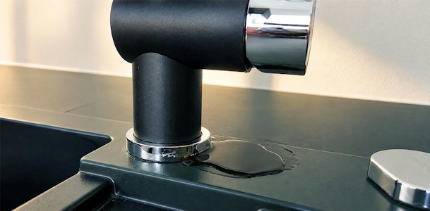 Plas water rond de voet van keukenkraan door een verharde afdichtring of losgetrilde bevestigingsmoer
