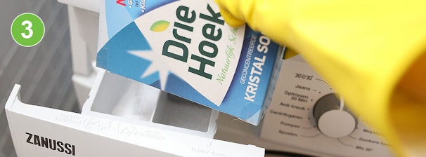 Kristalsoda toevoegen aan wasmachine: pak Driehoek kristalsoda wordt in het wasmiddelbakje van een Zanussi wasmachine geschud