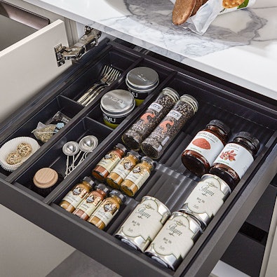 Georganiseerde kruidenlade met potjes en bestekindeling.