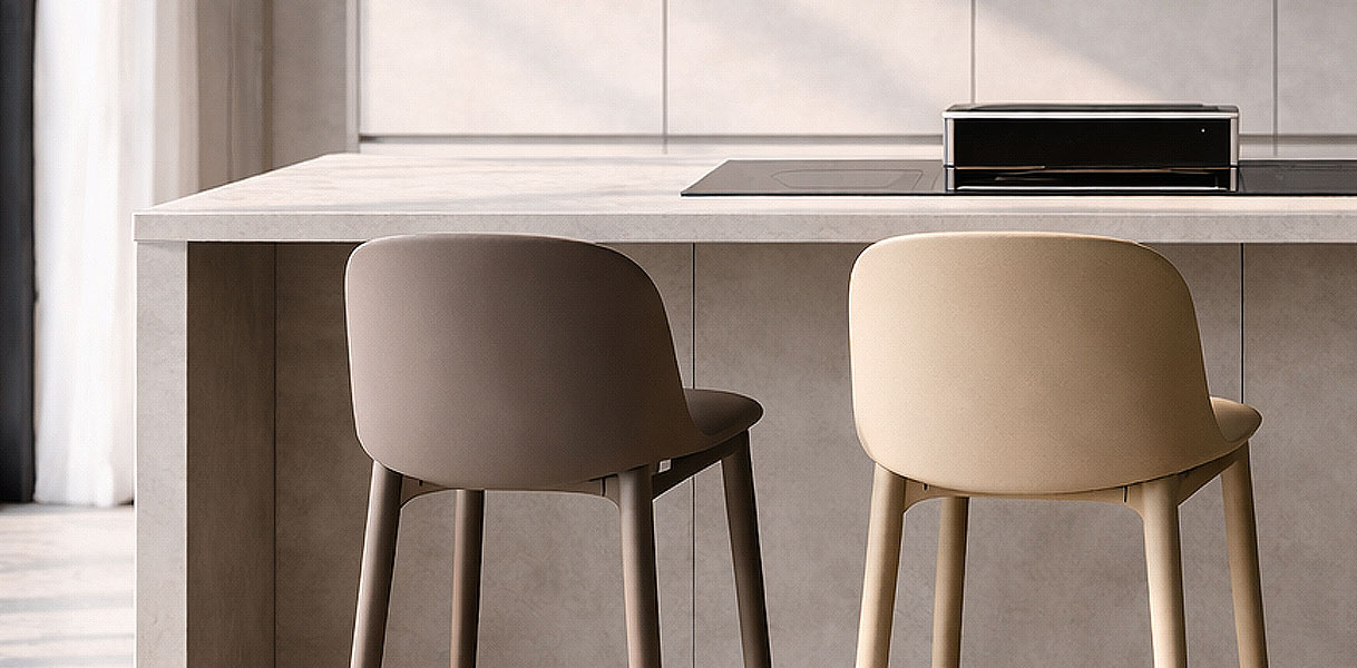Twee moderne kunststof barkrukken in zand en beige tint met houten poten naast een wit keukeneiland met ingebouwde kookplaat