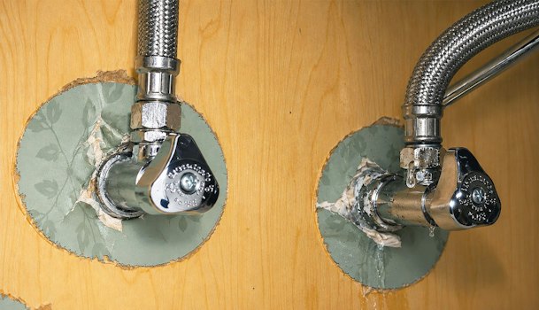 Druppelende koppeling tussen hoekstopkraan en flexibele aansluitslang onder het aanrecht bij een lekkende keukenkraan