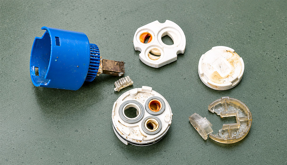 Uit elkaar gehaalde cartouche met keramische schijven vol kalkaanslag waardoor de uitloop blijft lekken