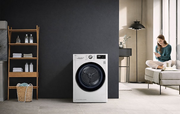 LG ThinQ droger in een wasruimte met een vrouw die de droger op afstand bedient via de app