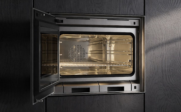Gaggenau combimagnetron met volledig geopende deur links of rechts draaiend ingebouwd in donkere keuken