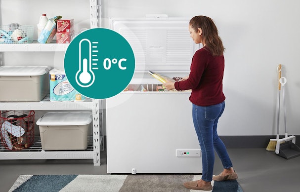Vrouw opent een vrieskist in een onverwarmde schuur met 0 graden pictogram, geschikt voor gebruik vanaf 0 °C omgevingstemperatuur