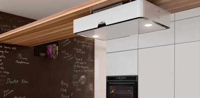 Witte afzuigkap met ledverlichting boven een kookplaat in een moderne keuken