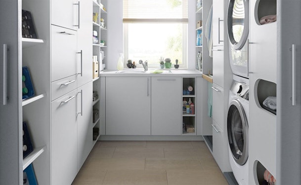 Maatwerk wasruimte met gestapelde wasmachine en droger, spoelbak en ingebouwde opbergkasten