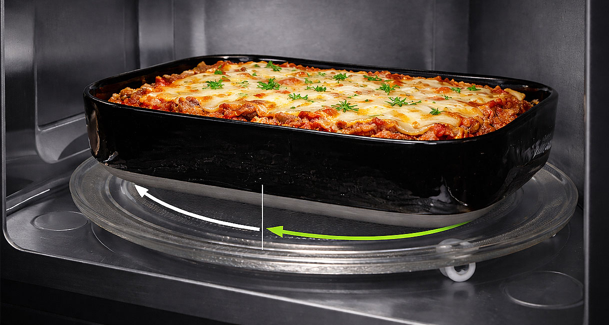 Lasagne op roterend draaiplateau in magnetron met pijlen die de ronddraaiende beweging voor gelijkmatige opwarming tonen