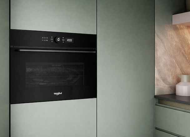 Whirlpool magnetron inbouw in moderne keuken met groene kasten en marmeren achterwand