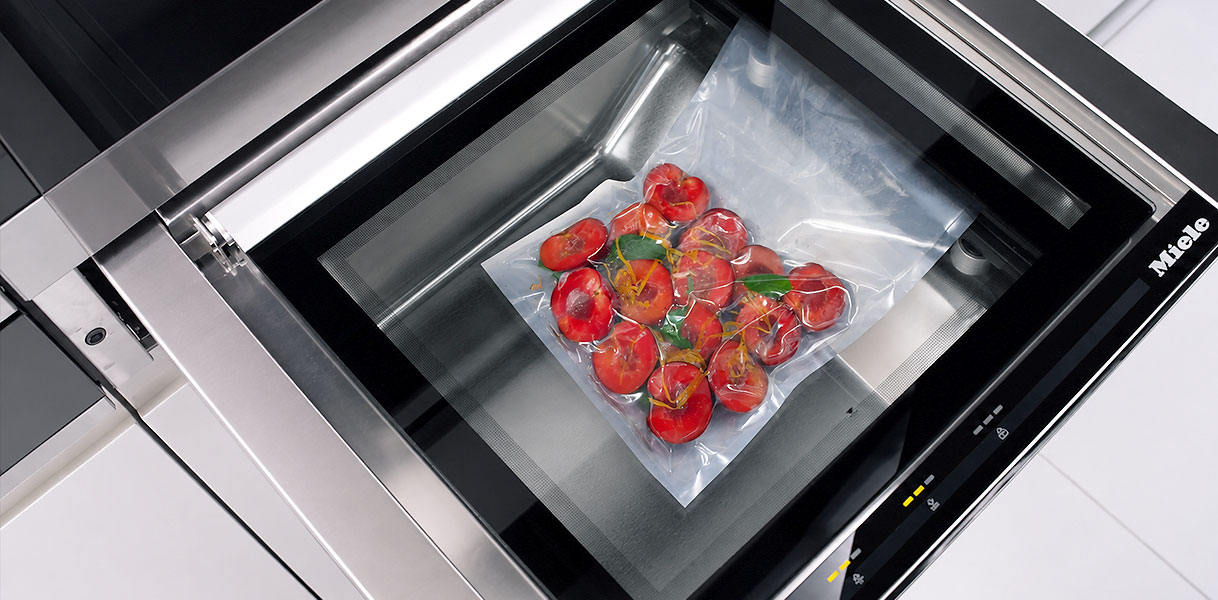 Vacuüm verpakte tomaten met kruiden op een plateau in een geopende stoomoven