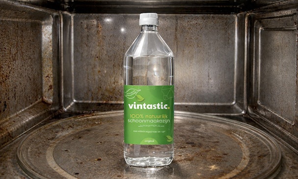 Fles Vintastic schoonmaakazijn in een vieze magnetron als effectief middel tegen aangekoekt vet en geurtjes