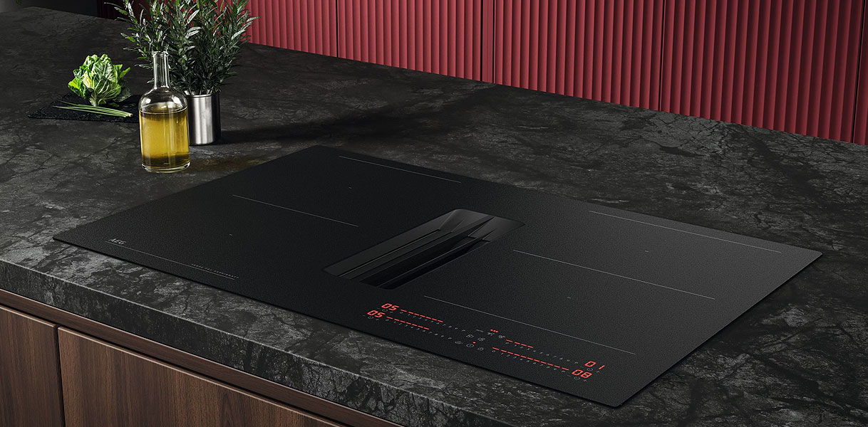 Mat zwarte inductiekookplaat met geïntegreerde afzuiging vlak ingebouwd in een donker keukenwerkblad.