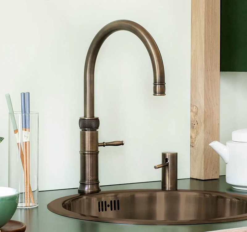 Quooker Classic Fusion kokendwaterkraan in messing patina finish boven een spoelbak, met zichtbaar warme bronzen kleur en verouderde uitstraling