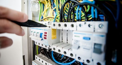Installateur werkt met gereedschap aan de automaten en bedrading in de meterkast