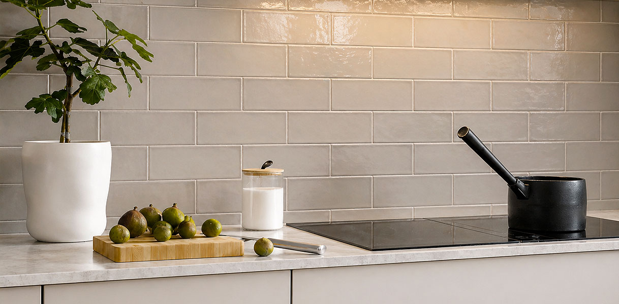 Crèmekleurige metrotegels als achterwand in keuken met inductiekookplaat en houten snijplank